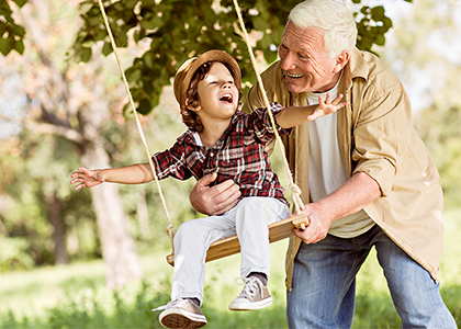 Grandpa pushing kid on a swing